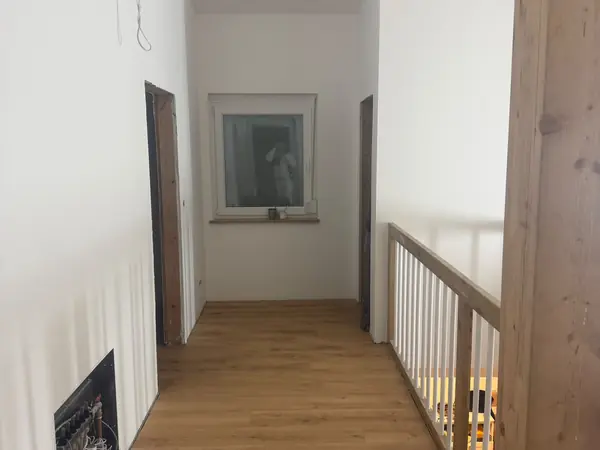 Galerie im Obergeschoss mit sichtbaren Holzbalken und neuem Boden